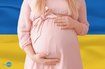 Mulher grávida veste um vestido rosa e segura a barriga, tendo ao fundo as cores azul e amarela da bandeira da Ucrânia No canto inferior esquerdo, destaca-se o logotipo azul 'Espnet'