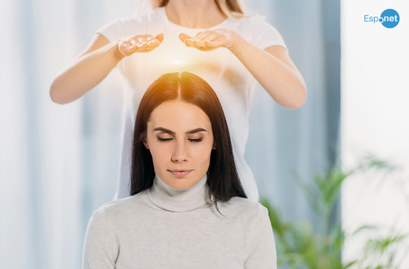 Mulher sentada de olhos fechados enquanto outra pessoa posiciona as mãos sobre sua cabeça, em um ambiente claro e tranquilo, sugerindo uma sessão de passe espiritual. No canto superior direito, destaca-se o logotipo azul 'Espnet'