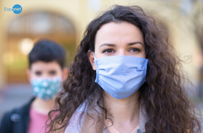 duas mulheres usando máscaras de proteção em tecido, cobrindo boca e nariz. Um em primeiro plano outra em desfoque